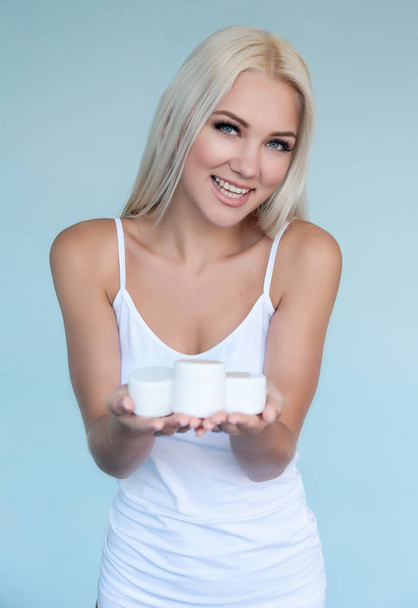 Luxury beautiful blonde girl or woman keep on hands  white jar with cream and choose a cream - 写真・画像