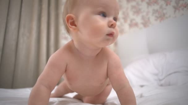 niedliche kleine Mädchen versucht, auf weißem Bett Zeitlupe kriechen - Filmmaterial, Video