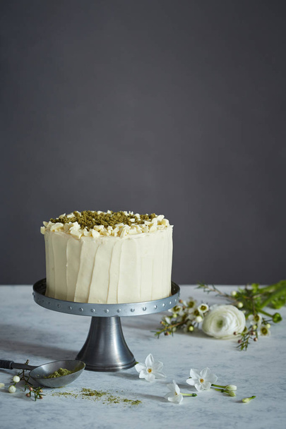 a cake on the cakestand decorated with nuts and ground rosemary - Fotografie, Obrázek