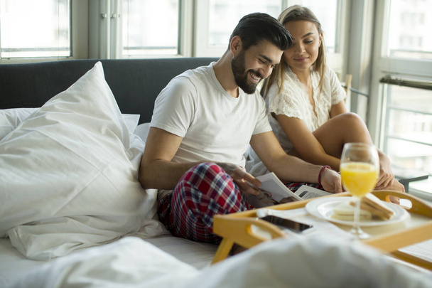 Пара завтракает в своей постели дома
 - Фото, изображение