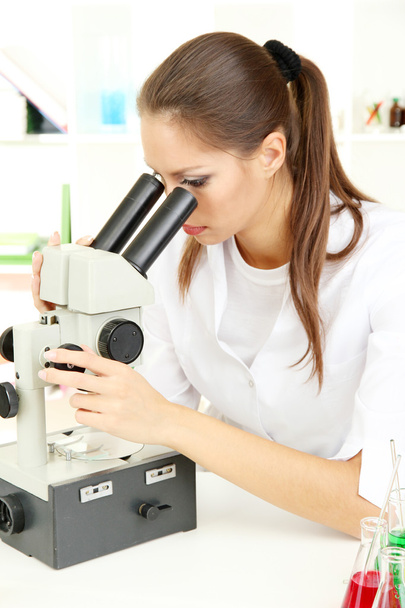 Young scientist looking into microscope in laboratory - Foto, imagen