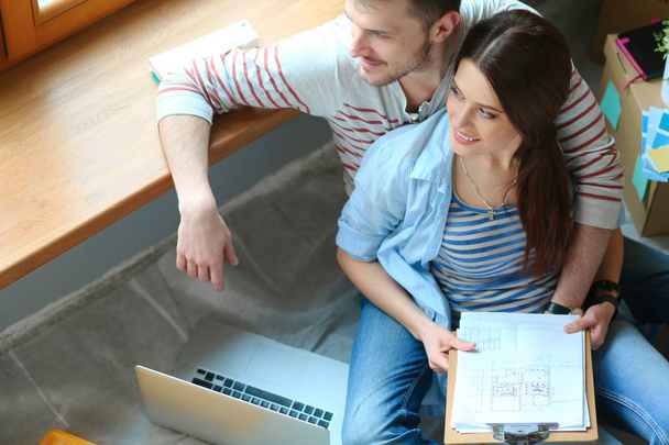 Young couple sitting on the floor of their new apartment - Foto, Bild