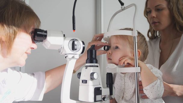 Doctor optometrist checks little girls eyesight - mother and child in ophthalmologist room - Photo, Image