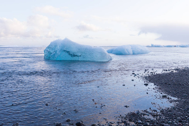 Ice cube breaking front glacier on black small rock beach - Фото, зображення