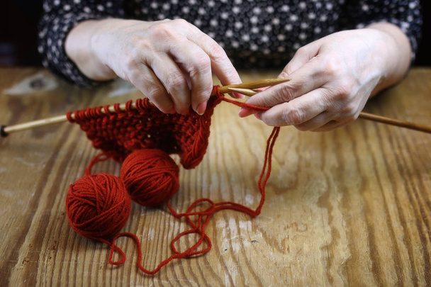 bejaarde vrouw houdt zich bezig met het breien van warme truien voor haar grand - Foto, afbeelding