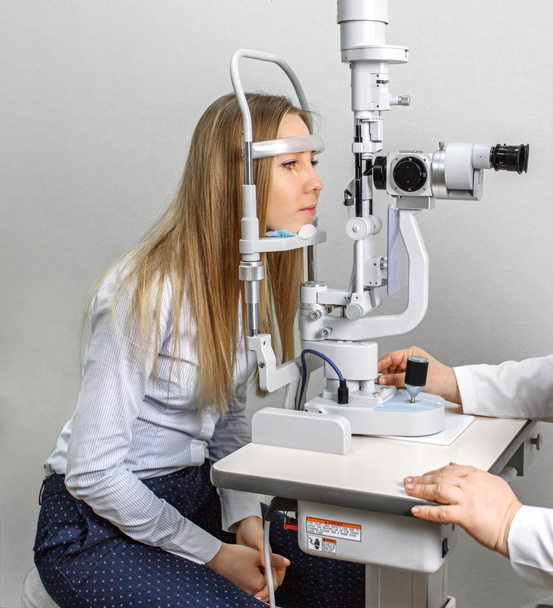 Attentive optometrist examining female patient on slit lamp in ophthalmology clinic - Φωτογραφία, εικόνα