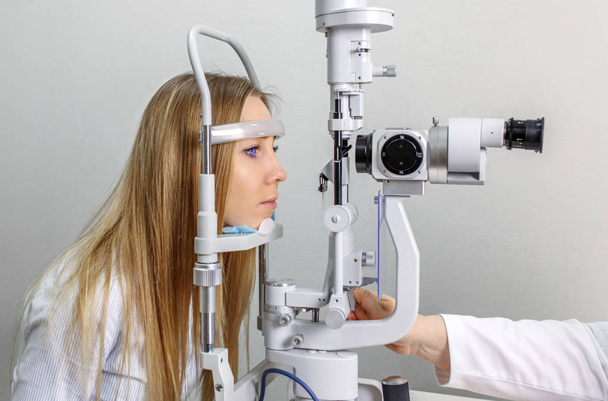 Attentive optometrist examining female patient on slit lamp in ophthalmology clinic - Fotografie, Obrázek