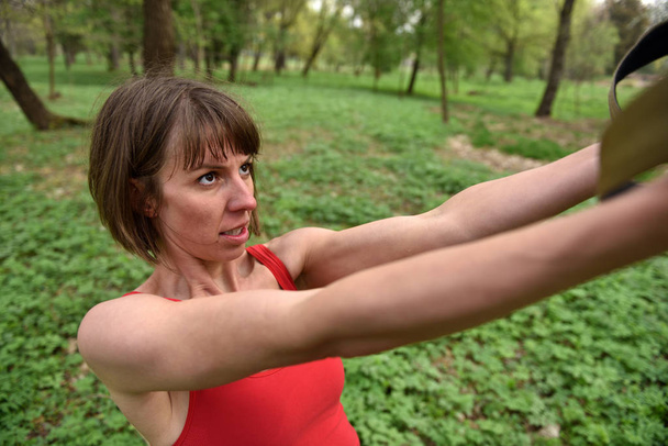 Femme faisant bras biceps curl training avec sangles de fitness trx
  - Photo, image