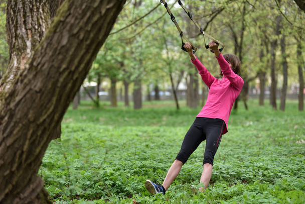 Woman doing arms biceps curl training with trx fitness straps  - Φωτογραφία, εικόνα