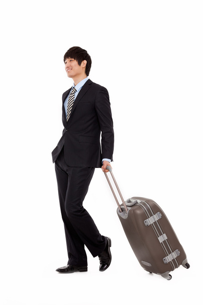 Businessman walking along pulling some travel luggage - Valokuva, kuva