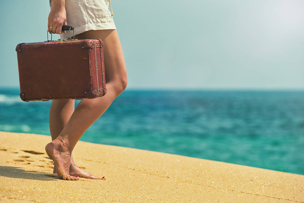 Beautiful girl with a old vintage suitcase in a beach - Photo, image