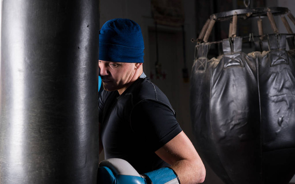 Male boxer with stern look in a hat and boxing gloves training w - Foto, Imagem