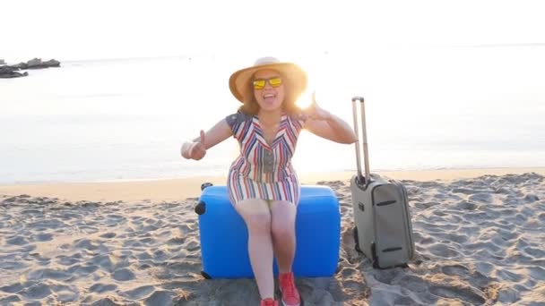 Felice giovane donna in vacanza con una valigia che mostra i pollici in su
 - Filmati, video