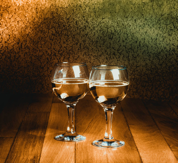 Two wineglasses of white wine on wooden old counter top - Foto, imagen