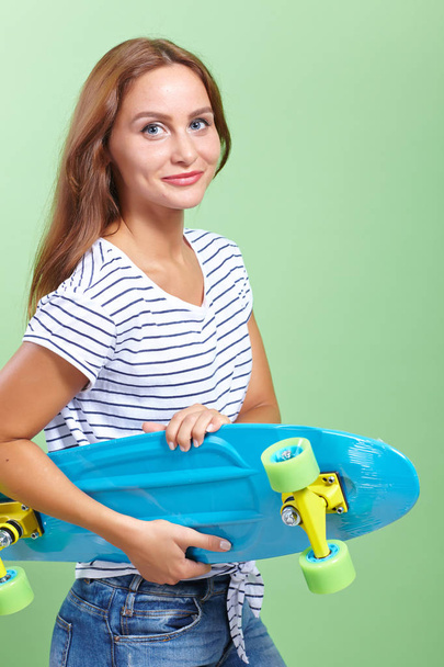 beautiful girl with skateboard on green background - Foto, Imagen