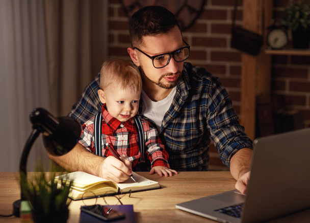 father and son baby work at home at computer in dark  - Photo, image