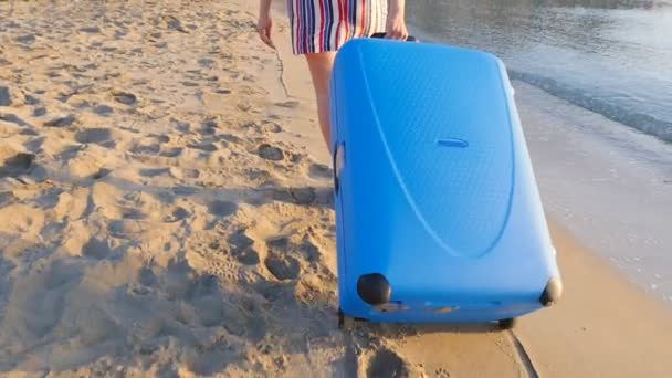Atraktivní mladá žena s kufrem na pláži. - Záběry, video