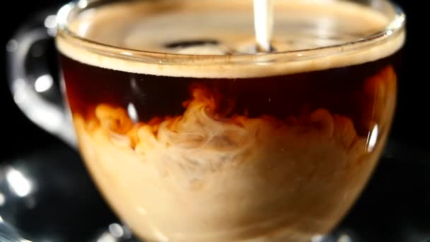 Milk pouring into coffee in a glass in slow motion - Video