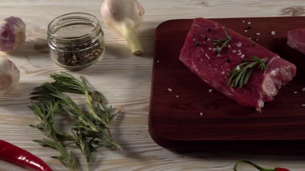 Beef fillet on a desk with pepper, rosemary and garlic. - Video, Çekim