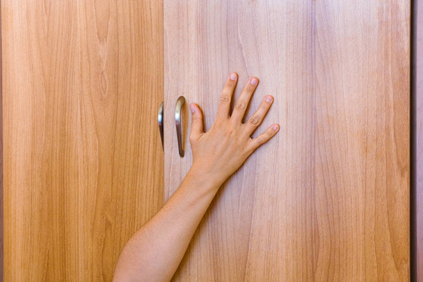 Person hand protruding from wardrobe door. - Foto, Imagen