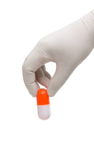 Ręka trzyma kapsułki lub tabletki w Rękawice medyczne  - Zdjęcie, obraz