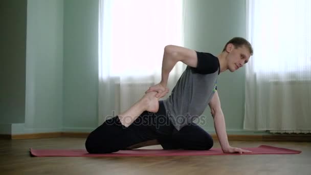 Um homem ioga faz um alongamento saudável no estúdio
 - Filmagem, Vídeo