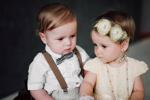 Hochzeit zweier Babys - Junge und Mädchen als Braut und Bräutigam verkleidet beim Spielen mit Spielzeugauto - Foto, Bild