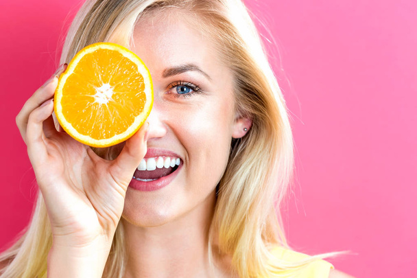Счастливая молодая женщина держит половинки апельсинов
 - Фото, изображение