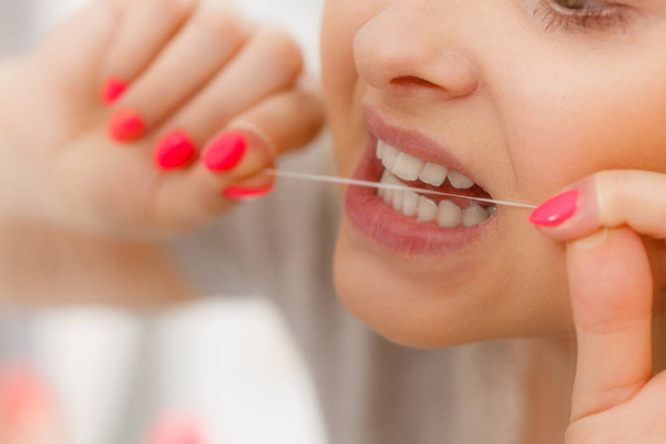 Woman cleaning her teeth using dental floss - Fotografie, Obrázek