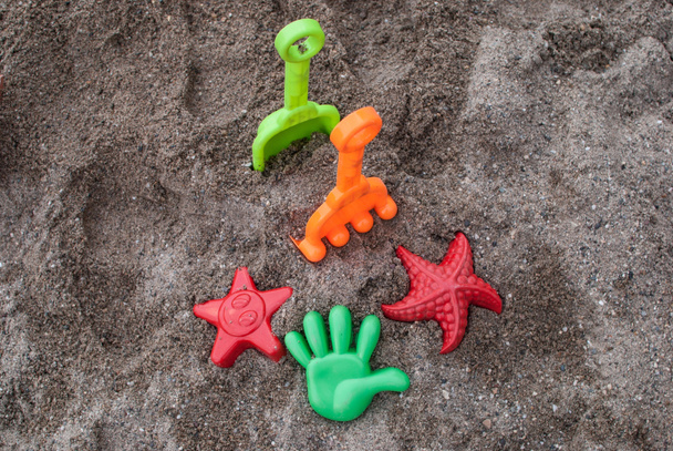 Niños juguetes de arena coloridos dispuestos en la arena de la playa
 - Foto, Imagen