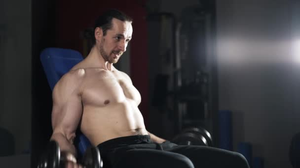 Man with naked torso doing a dumbbell exercise in gym - Materiał filmowy, wideo