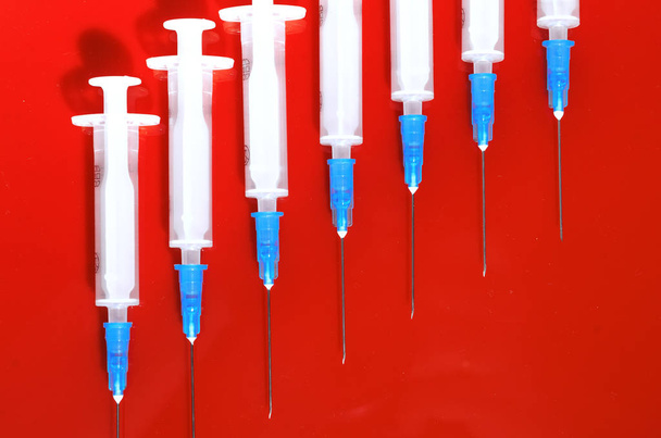 Syringe. Pills. Syringes with tablets on a red background. Injectors with medical preparations - Foto, imagen
