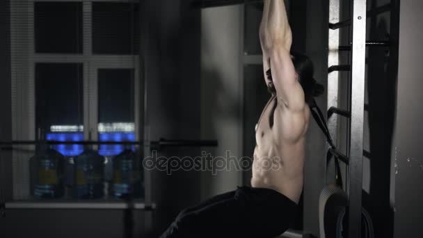 Side view of a man doing leg lifting on a horizontal bar - Video, Çekim
