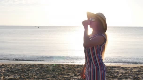 mladá žena pití kávy na pláži - Záběry, video