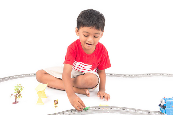 Sevimli Asya çocuk oynamak oyuncak tren beyaz arka plan üzerinde - Fotoğraf, Görsel