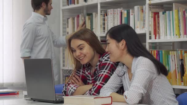 Deux filles étudient sur ordinateur portable à la bibliothèque
 - Séquence, vidéo