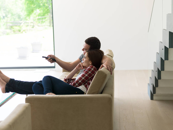 Giovane coppia sul divano a guardare la televisione
 - Foto, immagini
