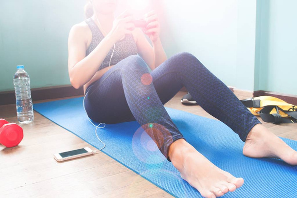 Fitness femminile che lavora su tappetino yoga con borraccia e attrezzature sportive, allenamento e concetto di stile di vita sano
 - Foto, immagini