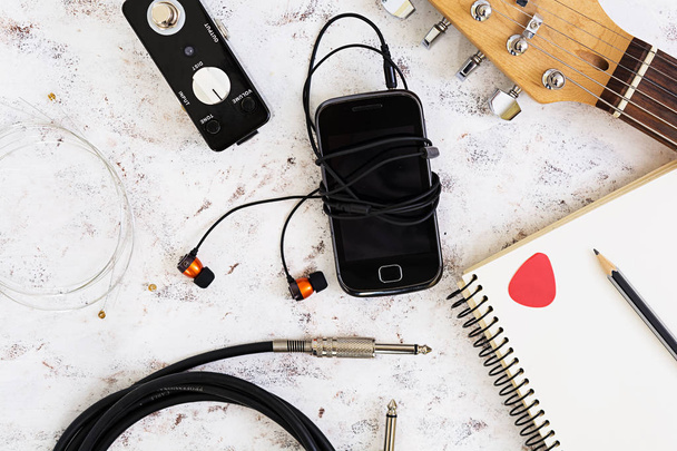 Music stuff. Guitar, guitar pedal, headphone, mobile phone on white background. Top view. Flat lay - Фото, изображение