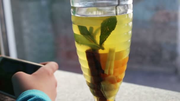 Giovane adolescente gioco su smartphone in caffè accanto al tè al limone con cannella
 - Filmati, video