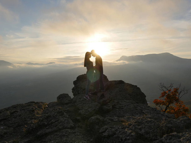 Silhouetten van jonge paar staande op een berg en op zoek naar elkaar op mooie zonsondergang achtergrond. Liefde voor jongen en meisje. - Foto, afbeelding