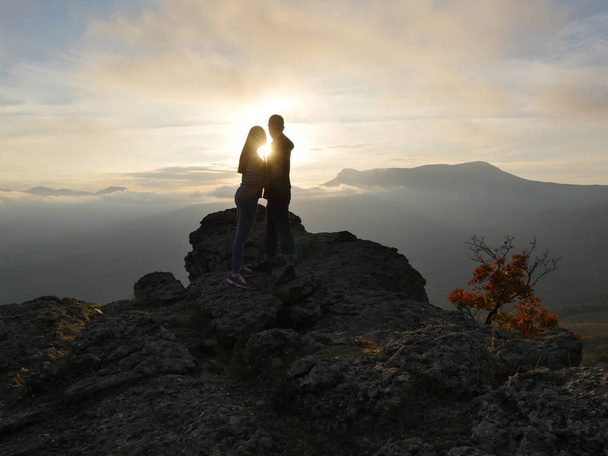 Silhouettes de jeunes couples debout sur une montagne et regardant les uns vers les autres sur un beau fond de coucher de soleil. Amour de mec et fille
. - Photo, image