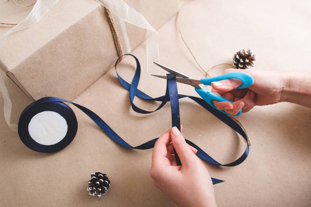 Packing presents. Hands with scissors cut ribbon. - Photo, Image