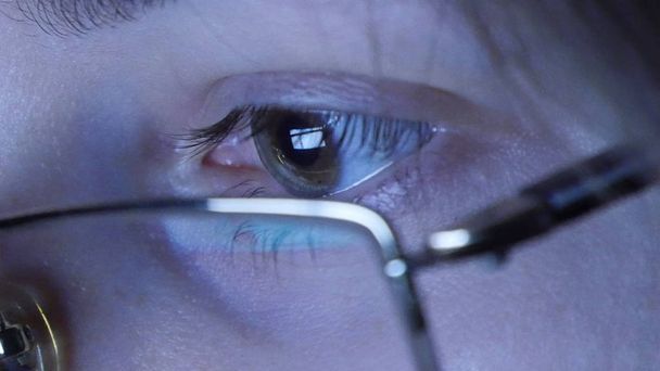 Close up shot of young girl in glasses surfing internet and watching video at night - Photo, Image