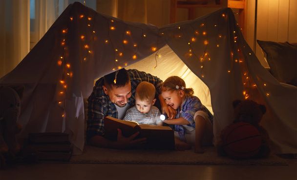 família feliz pai e filhos lendo um livro na tenda em hom
 - Foto, Imagem