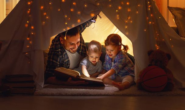 szczęśliwy ojciec rodziny i dzieci, czytanie książki w namiocie w hom - Zdjęcie, obraz