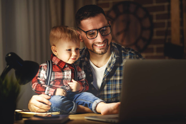 father and son baby work at home at computer in dark - Photo, Image