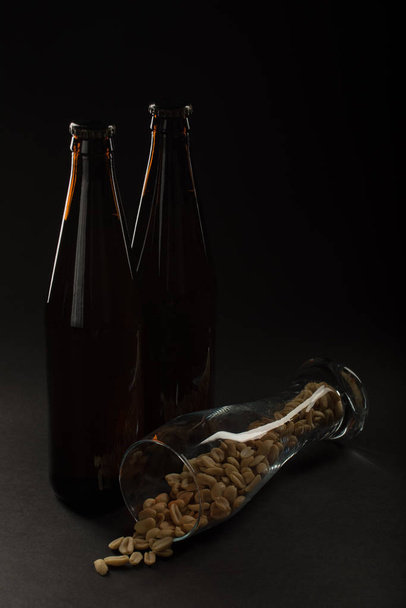 Altın bira bir şişe ve kadeh ve aperatif fındık, kalamar ve - Fotoğraf, Görsel