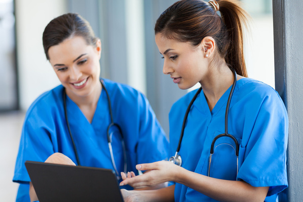 Two beautiful female healthcare workers using laptop - Fotó, kép