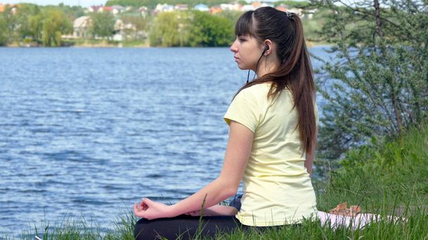 Fiatal nő, meditál, és a smartphone-ban fejhallgató a zene - Fotó, kép